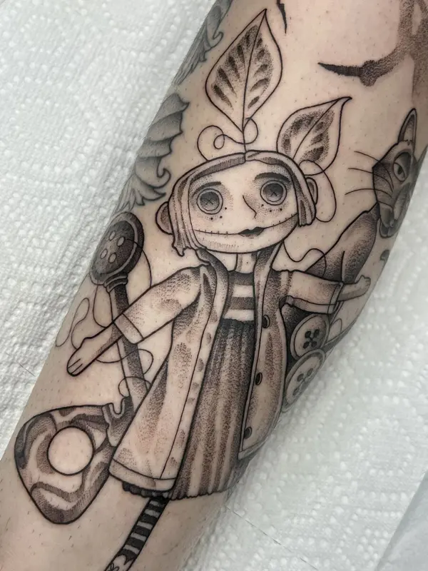 Coraline-inspired doll tattoo with a black cat, forearm
