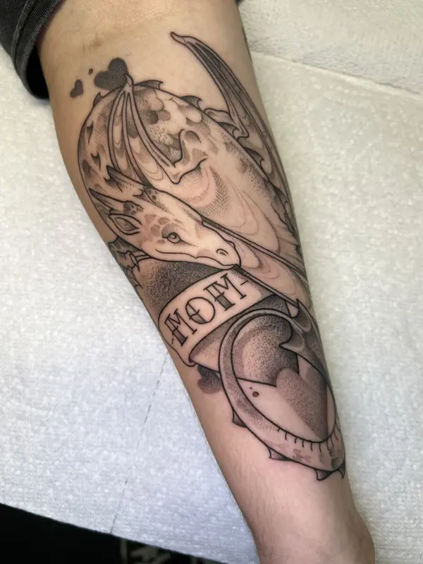 Giraffe-dragon hybrid tattoo with a 'mom' banner, forearm