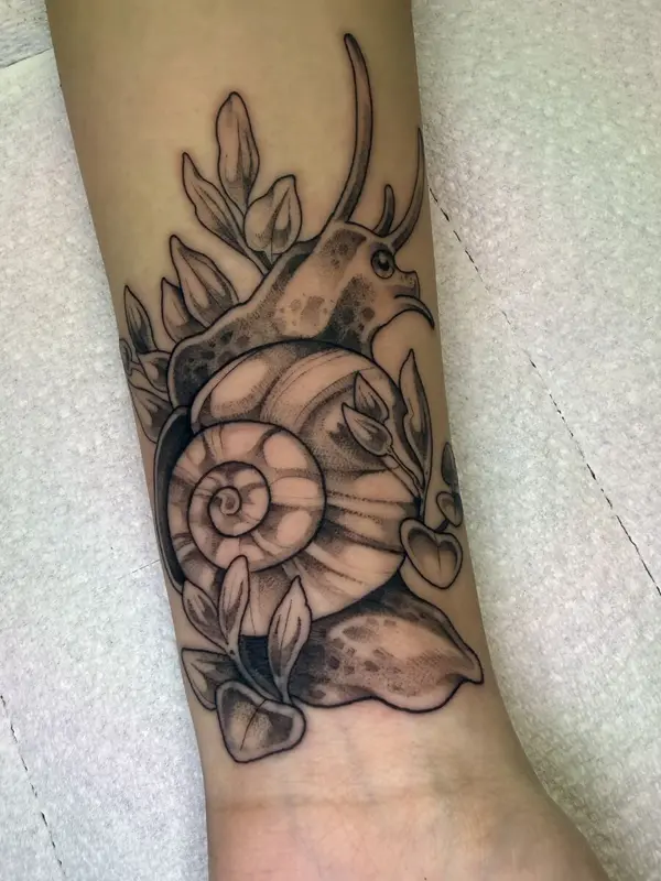 Illustrative garden snail tattoo with leaves, forearm